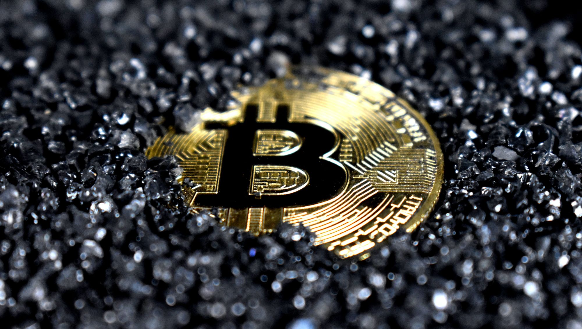đồng xu bitcoin phủ đầy cát đen