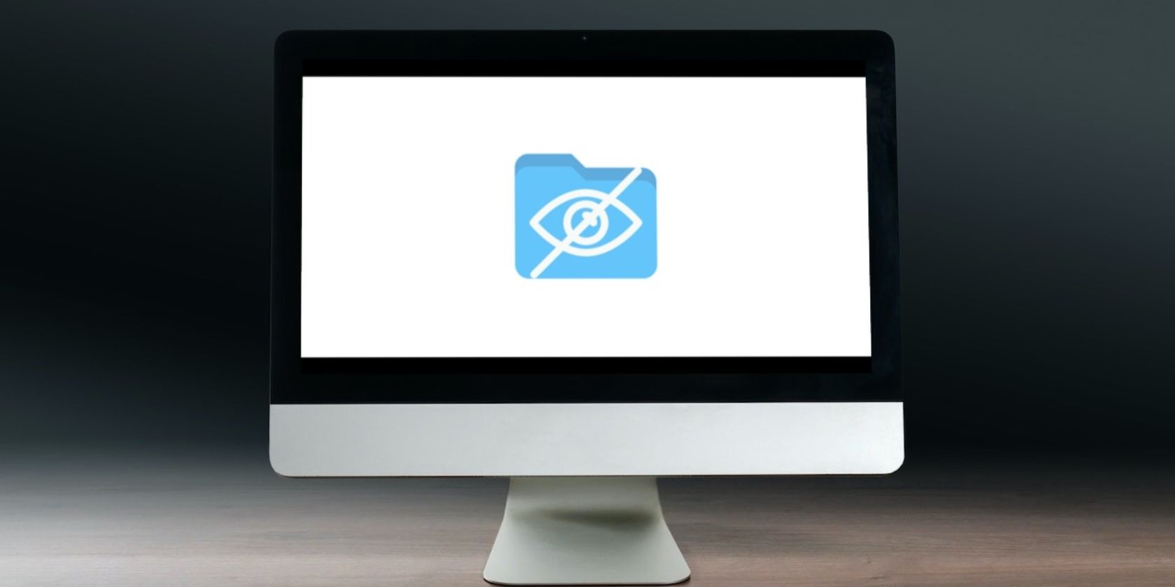 iMac on the wooden desk displaying folder icon and hidden eye symbol