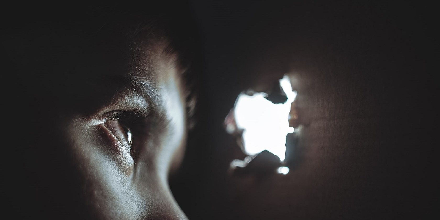 A person's eye peeping through a hole