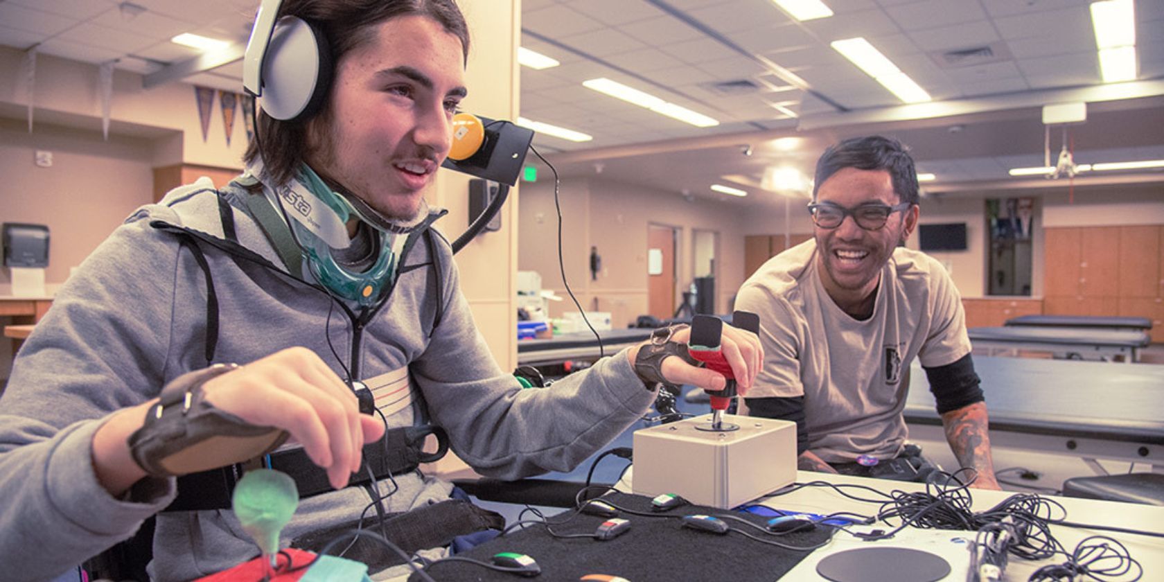 Người đang chơi và tận hưởng Bộ điều khiển thích ứng Xbox cùng với các Công cụ hỗ trợ tiếp cận khác