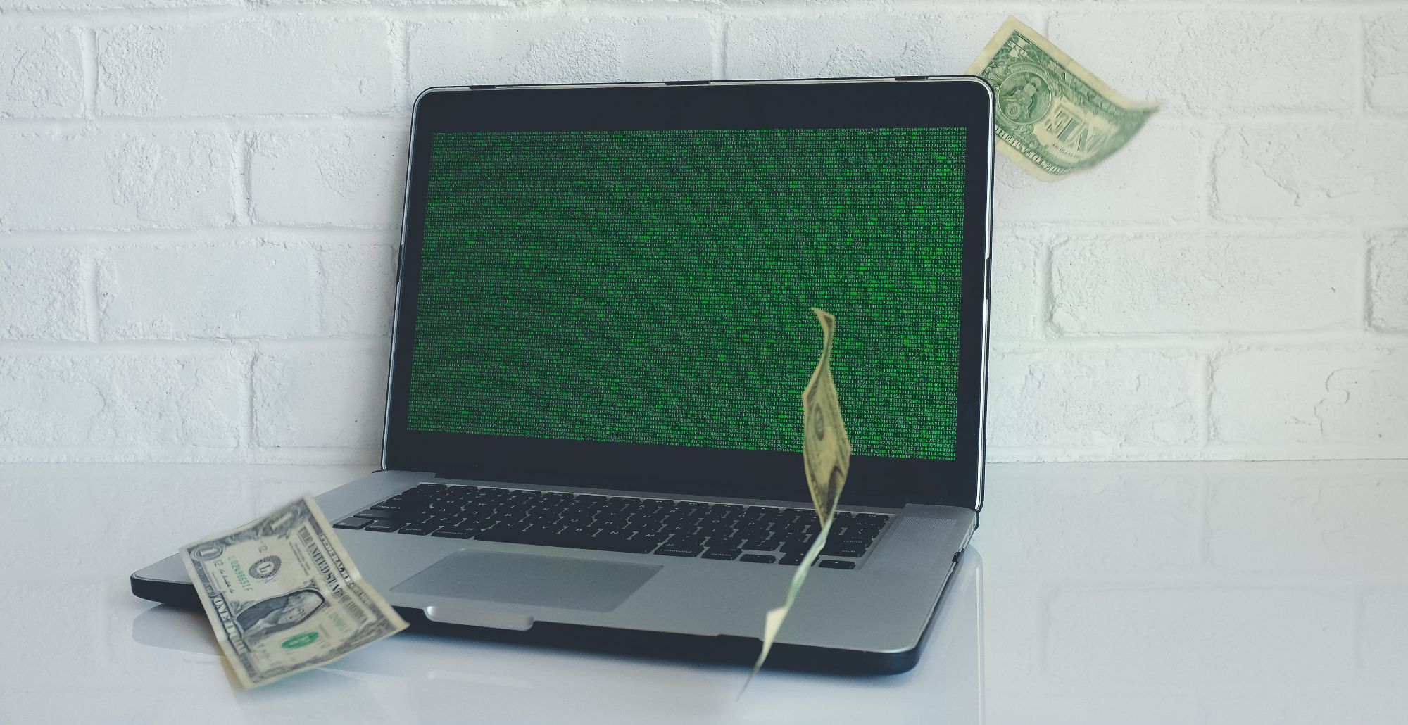 hóa đơn USD rơi trên máy tính xách tay với màn hình xanh