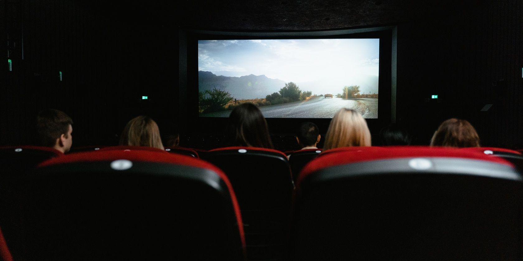 People sitting at a movie theater with red seats