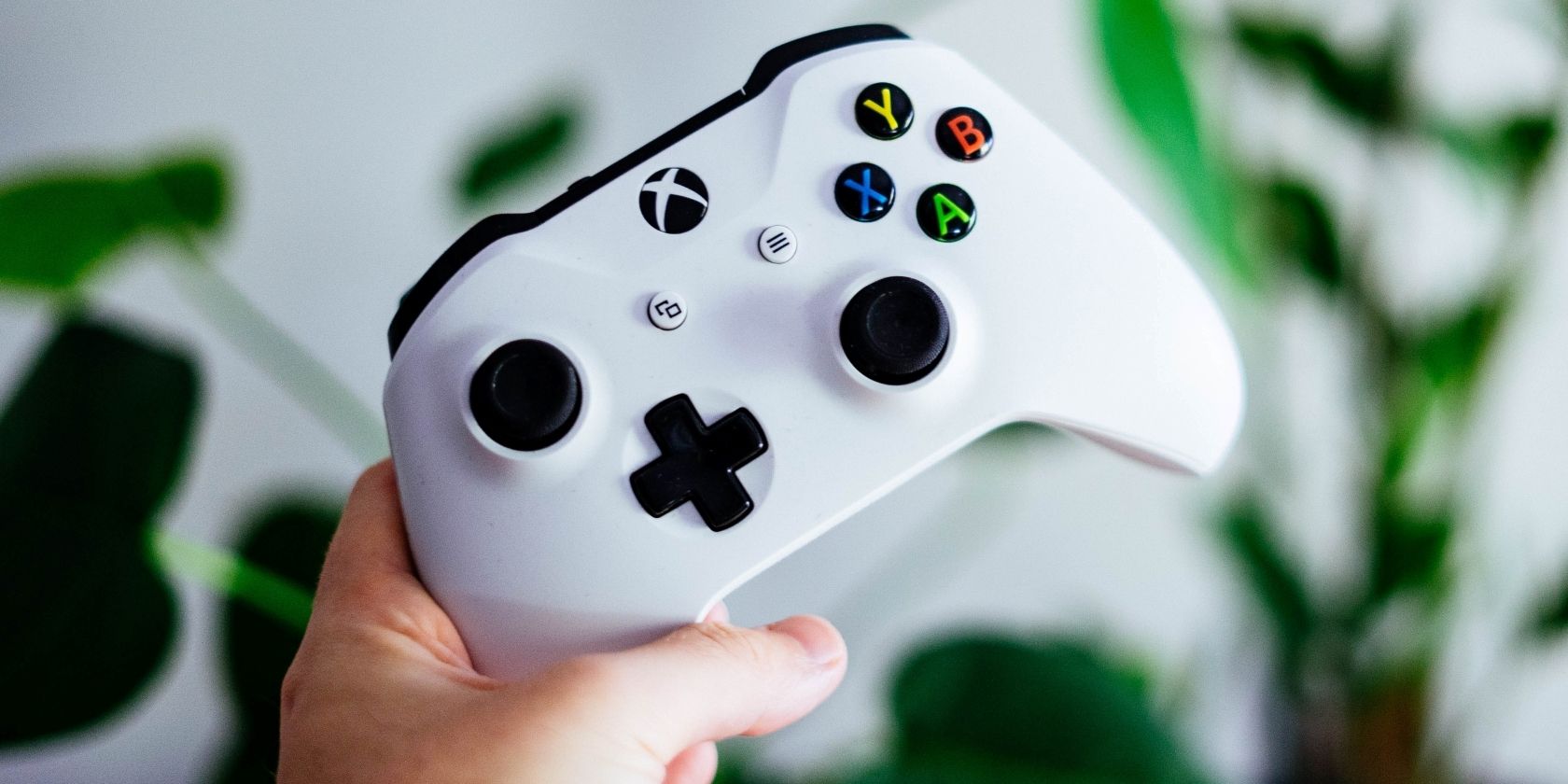 Bức ảnh chụp một người đàn ông đang cầm Bộ điều khiển Xbox One màu trắng 
