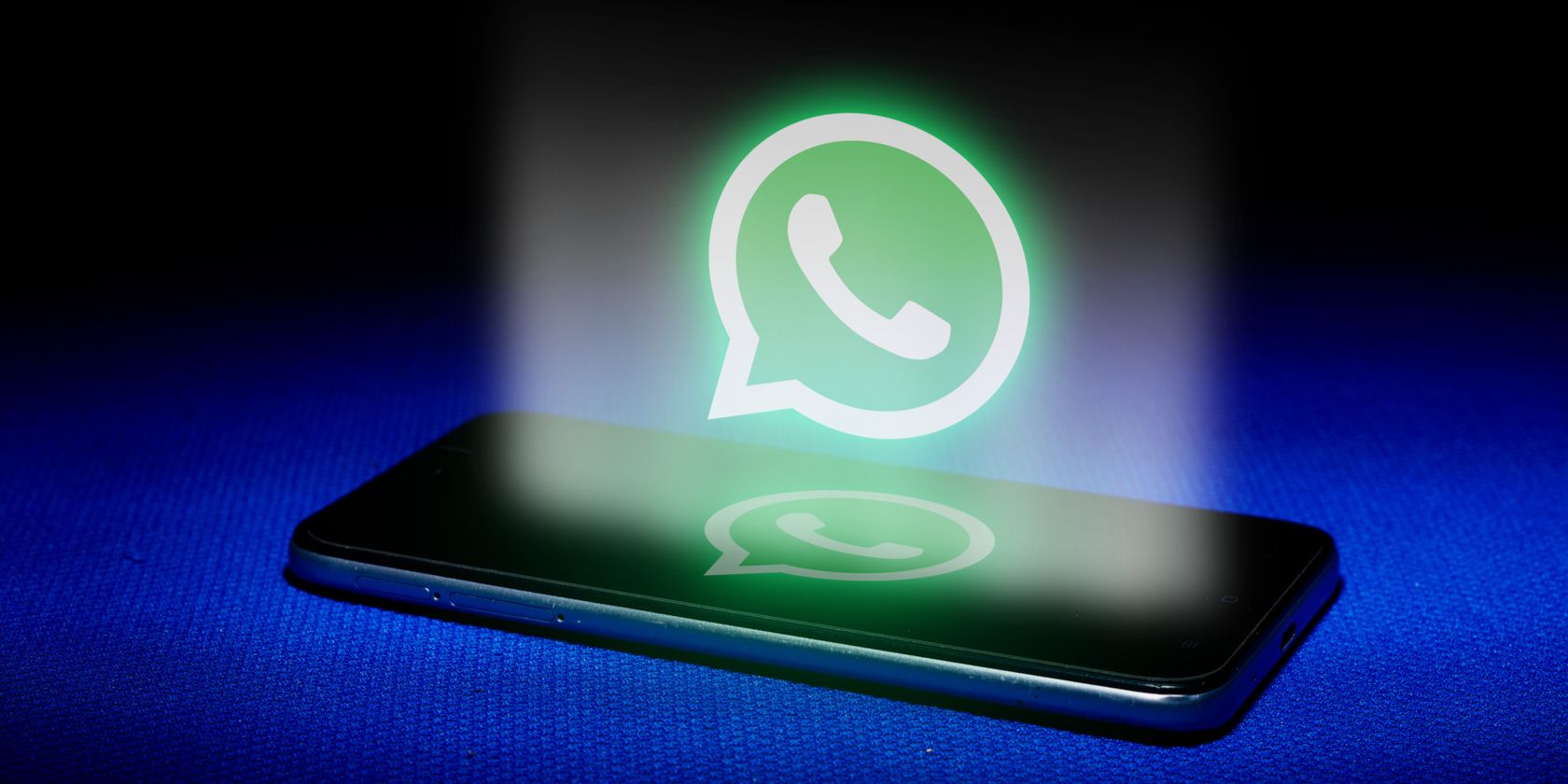 WhatsApp là gì và tại sao nó lại phổ biến như vậy? Glowing WhatsApp logo above smartphone