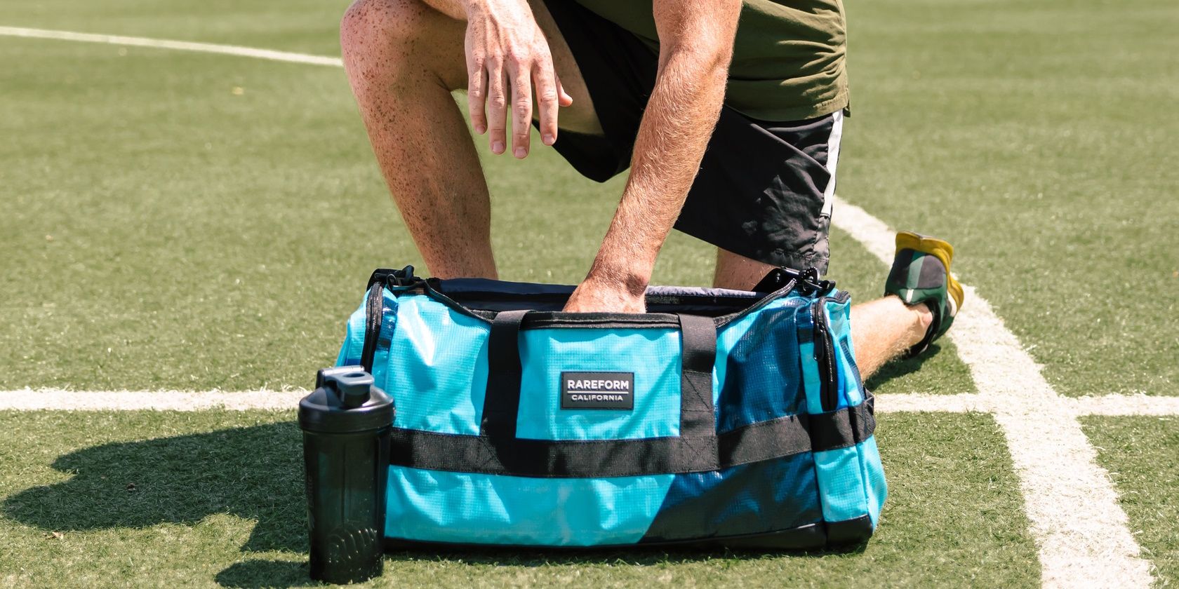man kneeling next to blue gym bag outside