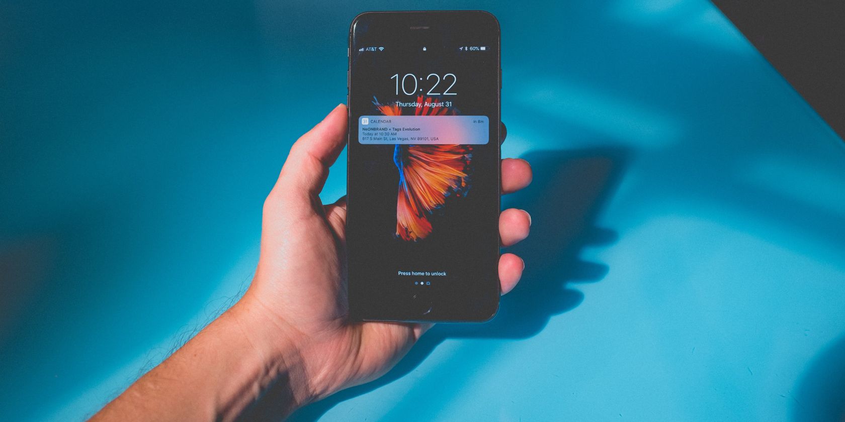 Tại sao Apple lại xóa hình nền động khỏi iOS 16? Hand holding an iPhone, showing the lock screen, on a blue table