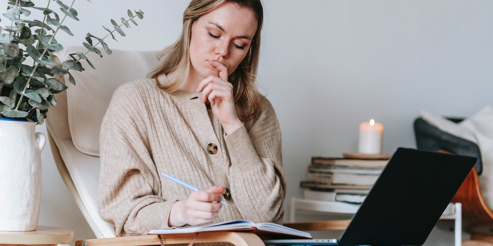 A person sitting with a laptop computer and taking notes