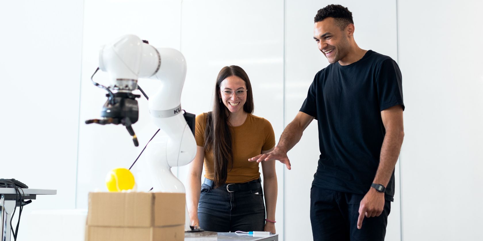 người đàn ông và người phụ nữ làm việc trên một cánh tay robot