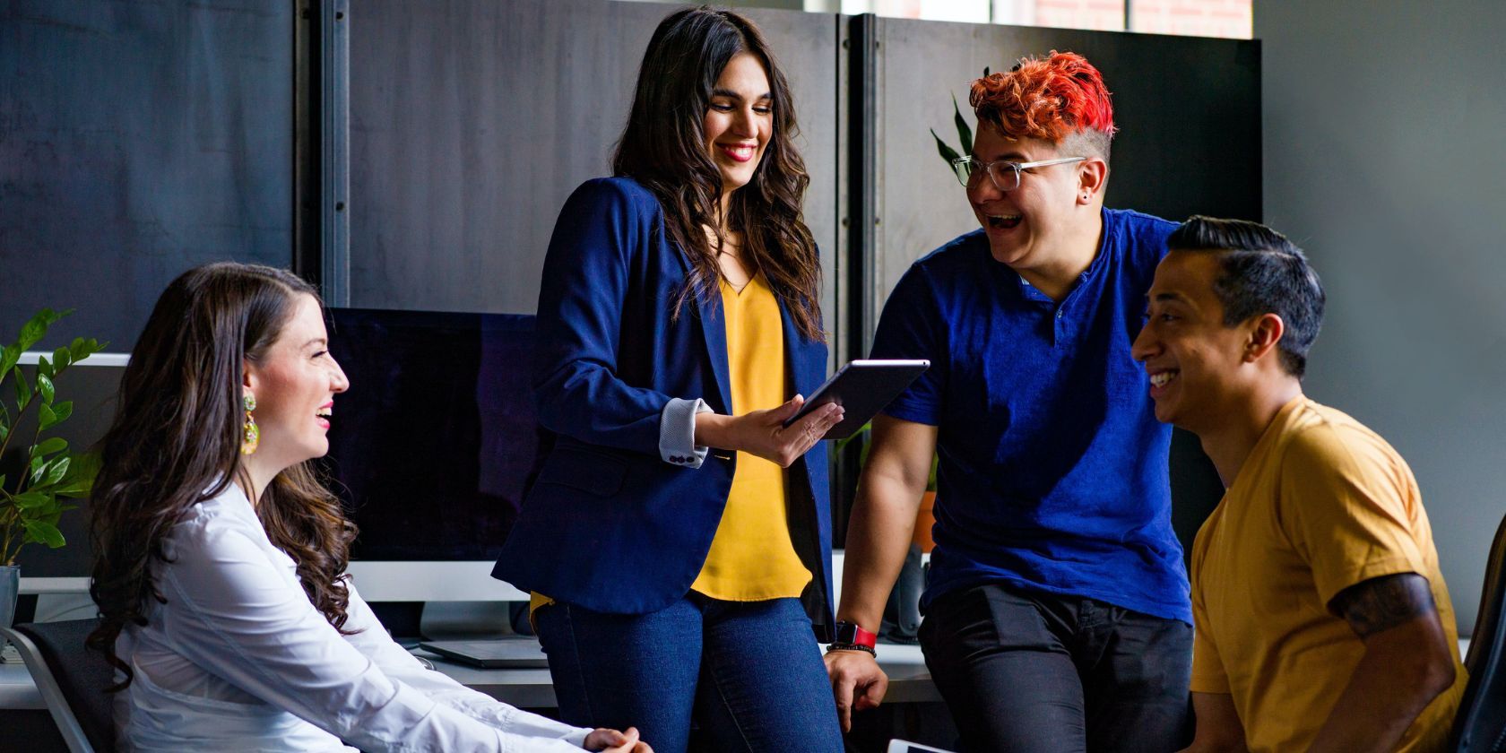 four people talking and smiling in the office