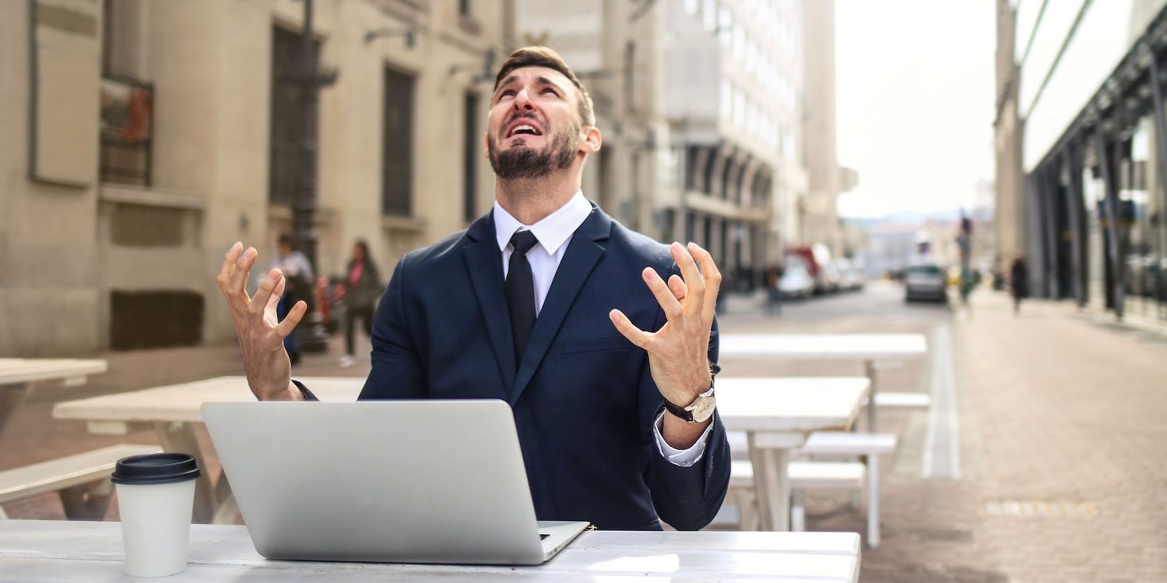Person looking up in frustration with a laptop and a cup of coffee on the table