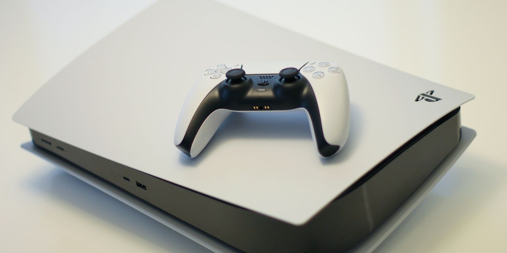 Cách ghi lại đoạn phim PS5 của bạn bằng lệnh thoại White PS5 lying horizontally with a white controller on top of it
