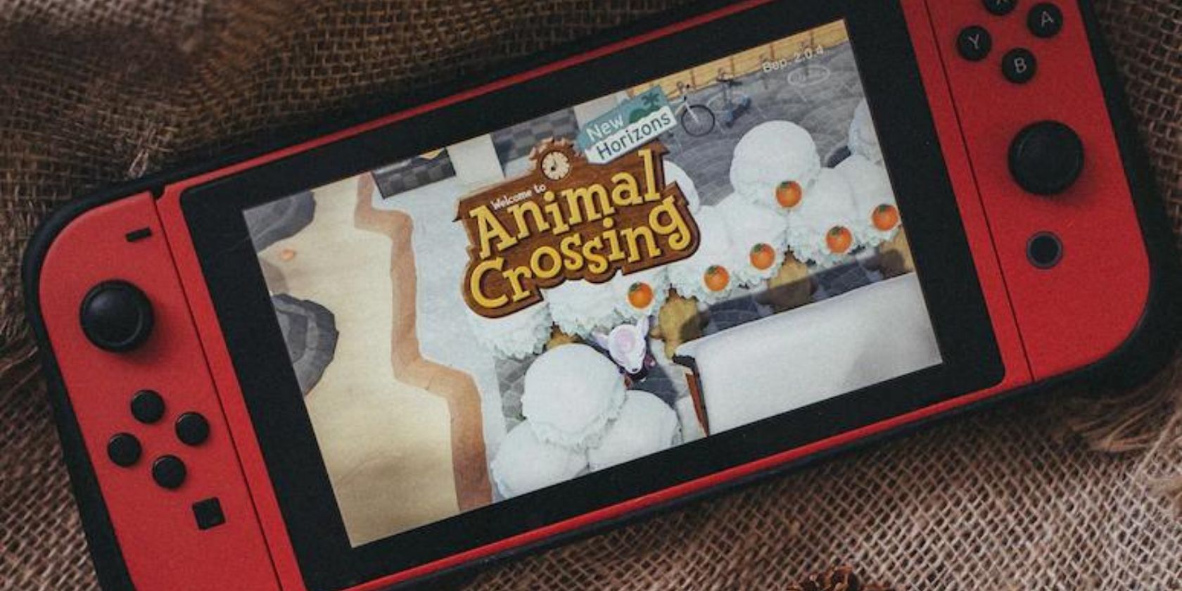 Bảng điều khiển Nintendo Switch màu đỏ chơi Animal Crossing New Horizons trên nền vải