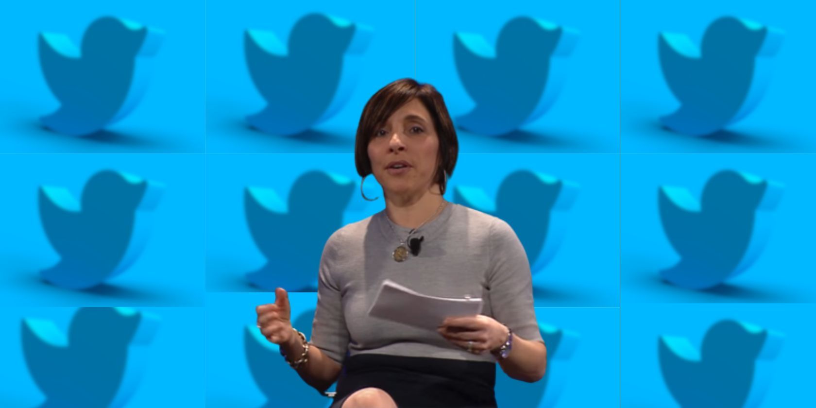 Linda Yaccarino Holding Paper and in front of Twitter Bird Logos
