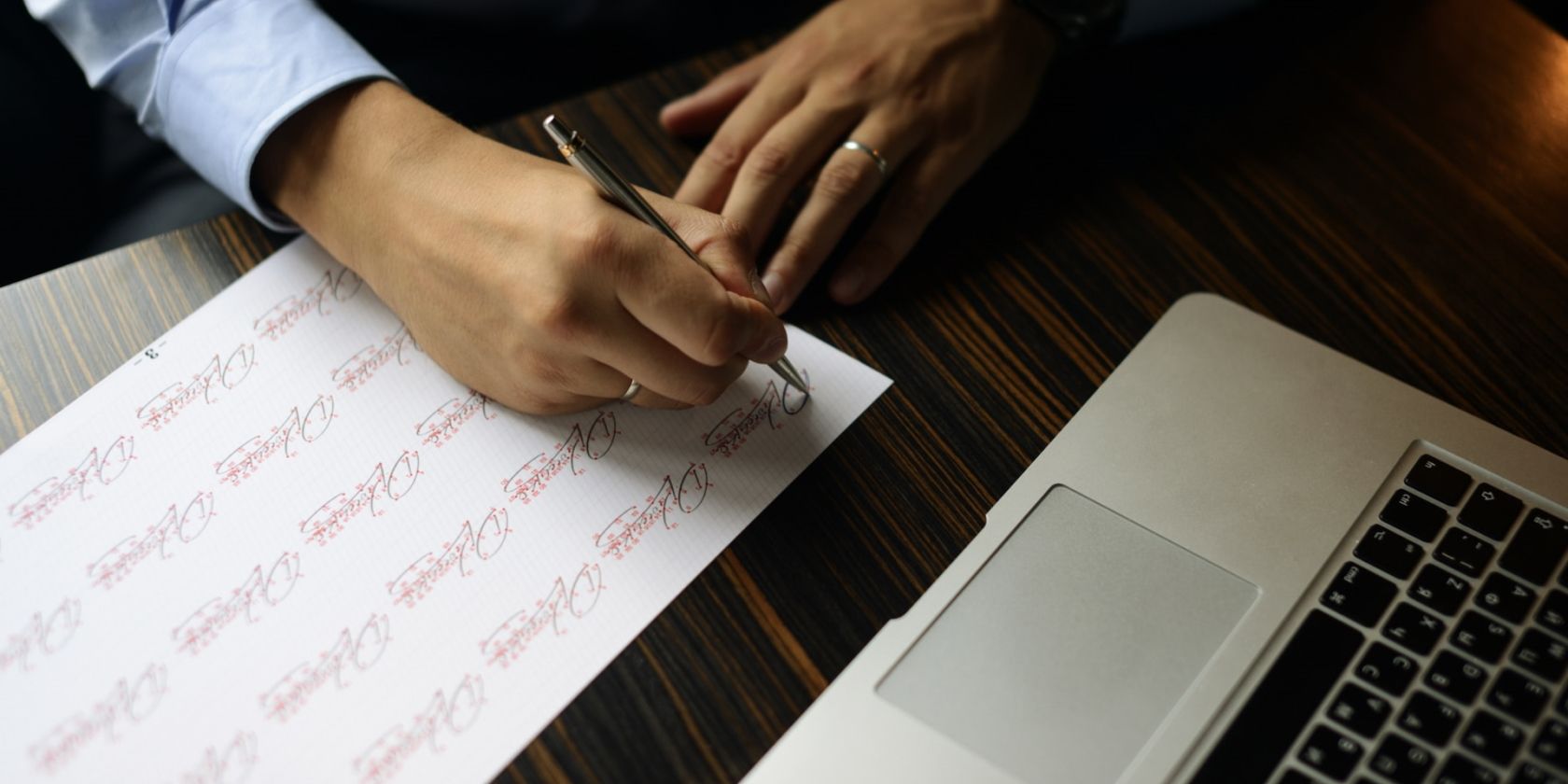 person signing next to a MacBook