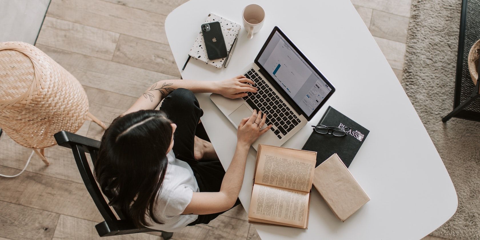 Woman with laptop and books on a white table