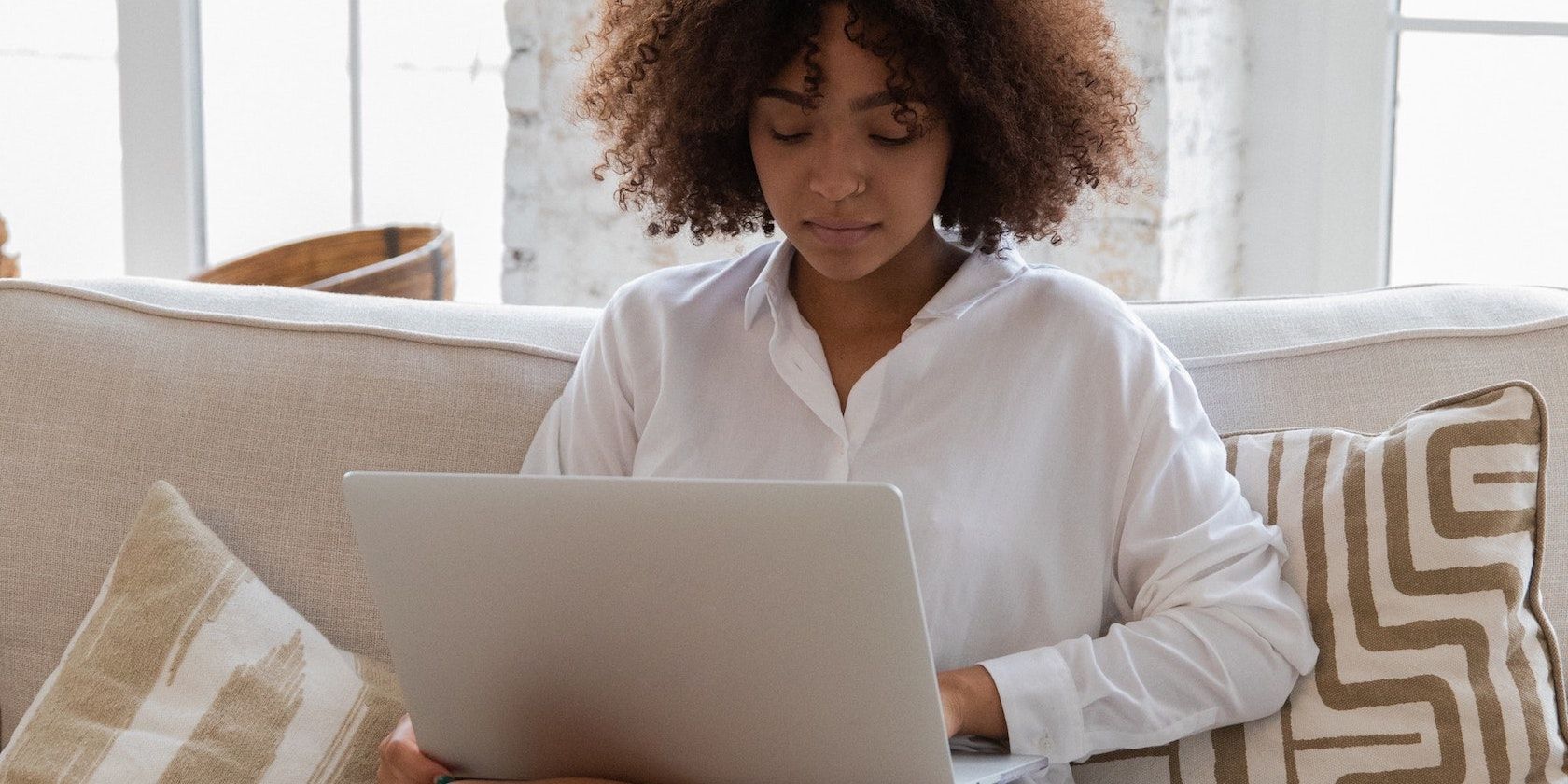 Woman seated on a couch working on a laptop