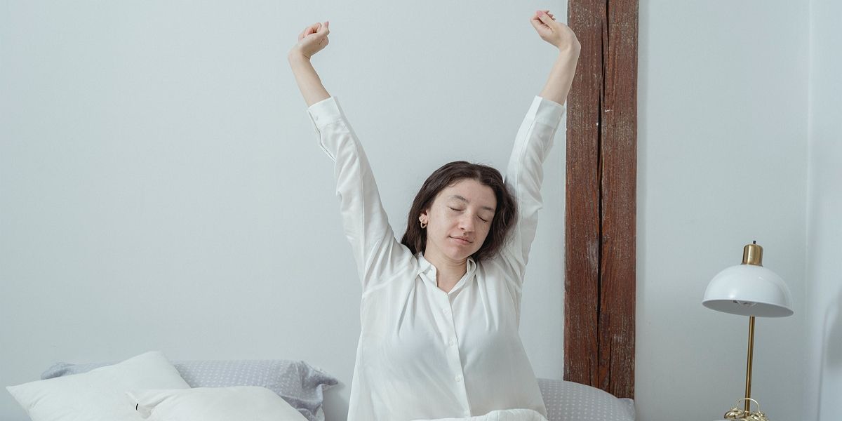 người phụ nữ buồn ngủ thức dậy trên giường vào buổi sáng