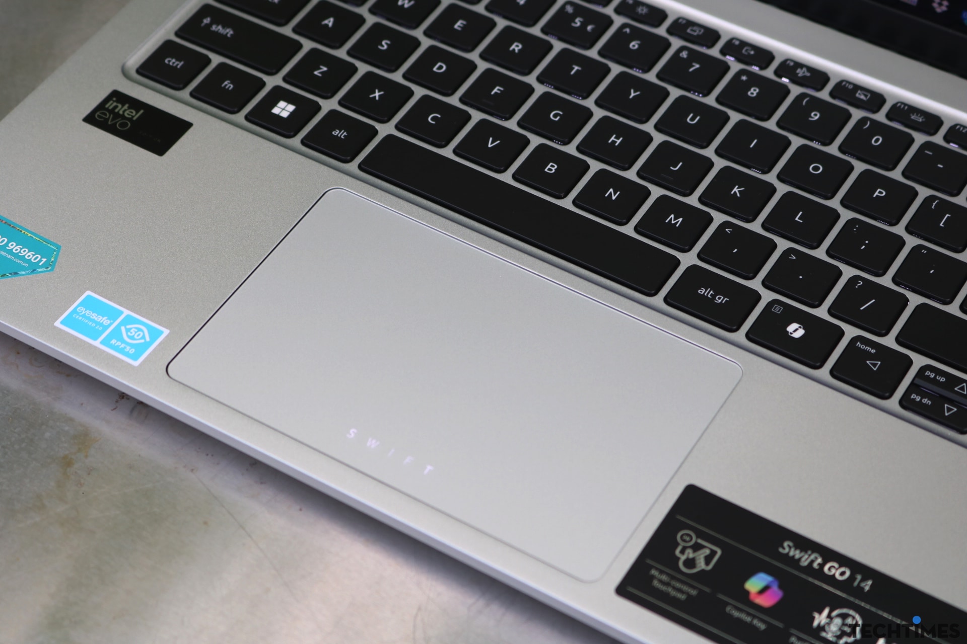 Đánh giá Acer Swift Go 14 AI OLED (SFG14-73): Màn hình đẹp, chức năng AI hữu ích TechTimes Vietnam Cận cảnh bàn di chuột lớn với logo SWIFT có đèn nền ấn tượng.